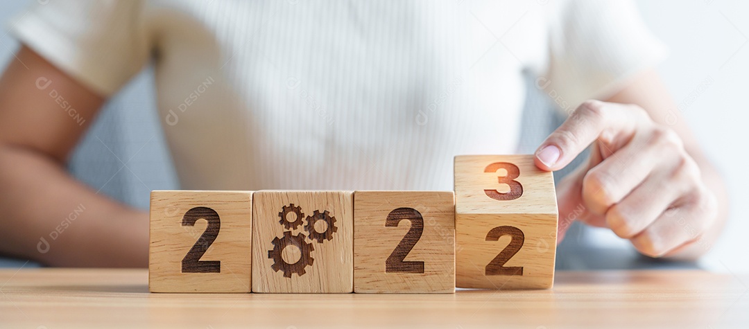 Mão de mulher mudar 2022 para 2023 bloco com ícone de engrenagem.