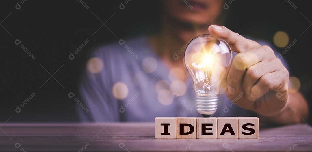 Mão tocando na lâmpada no bloco de madeira com Word Ideas