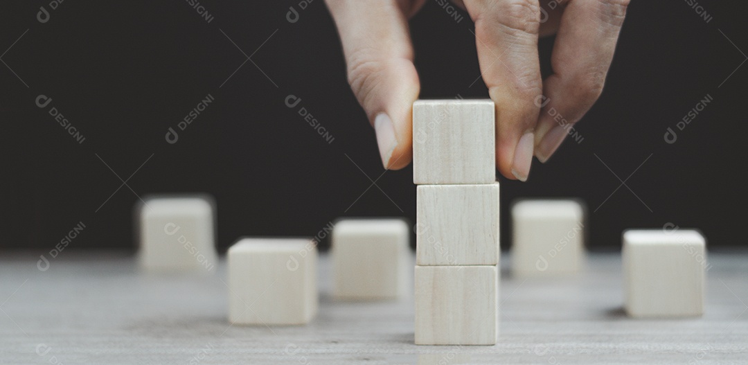 Hand arranging the stacking of three wooden cubes