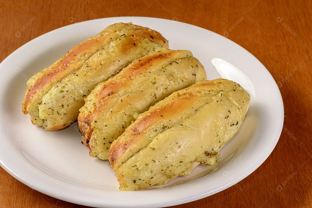 Três pães de alho em chapa branca na mesa de madeira. Pão de alho brasileiro.