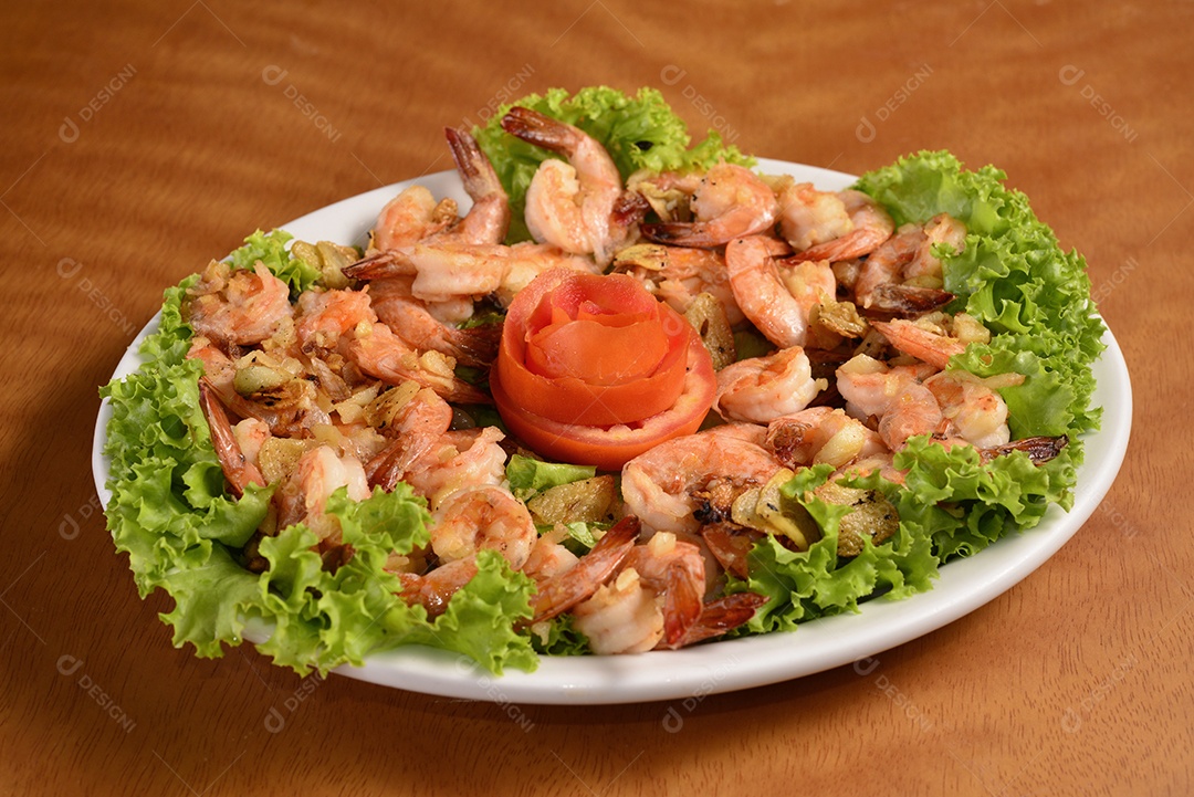 Camarões de alho em chapa branca na mesa de madeira. cozinha brasileira.