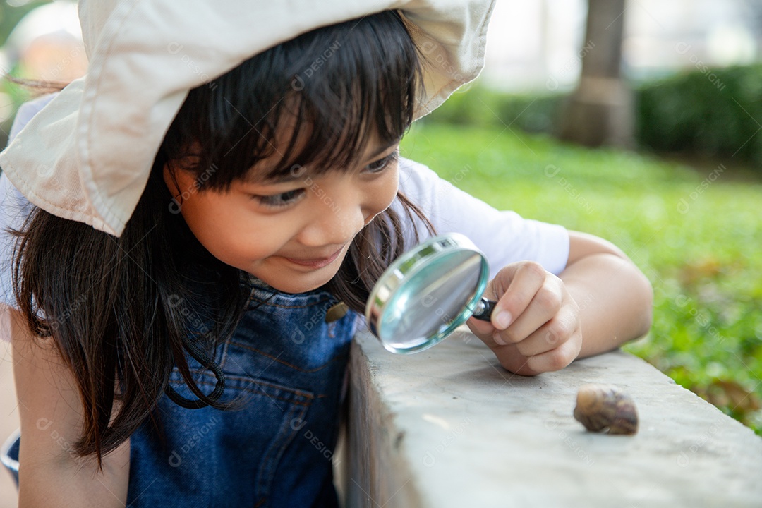 Garota criança feliz explorando a natureza com uma lupa