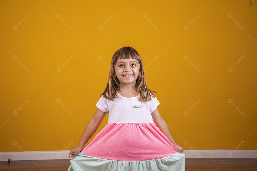 Linda menina criança sorridente sobre fundo amarelo
