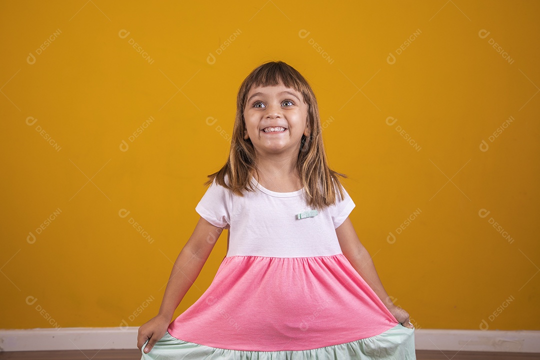 Linda menina criança sorridente sobre fundo amarelo
