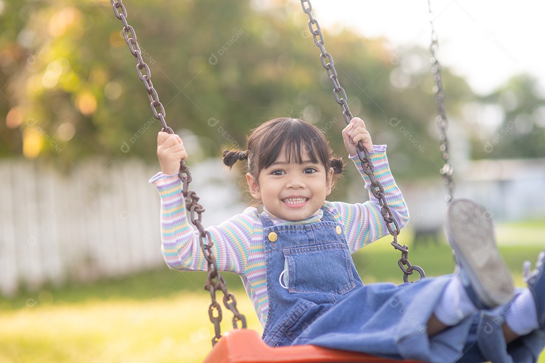 Menina asiática brincando no playground ao ar livre