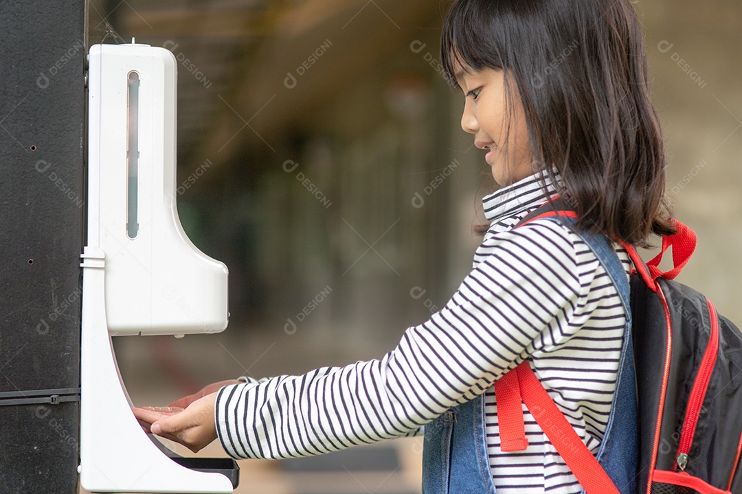 Menina criança usando dispensador automático de gel de álcool pulverizando