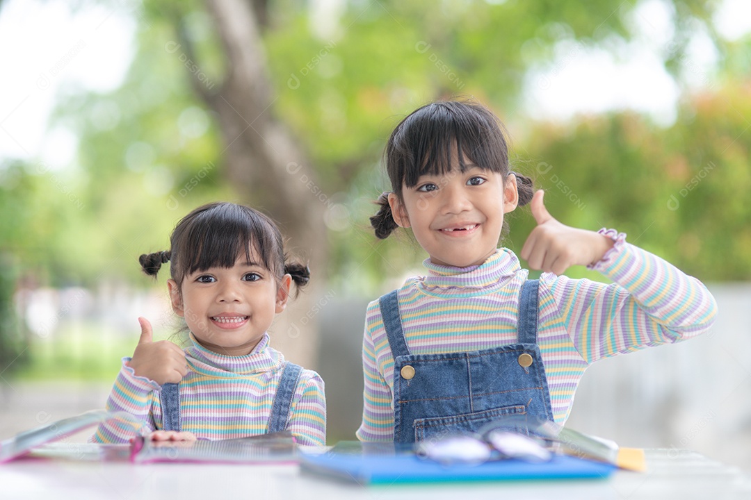 Duas meninas asiáticas estudantes lendo o livro na mesa.