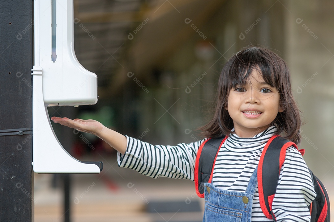Meninas criança usando dispensador automático de gel de álcool pulverizando.