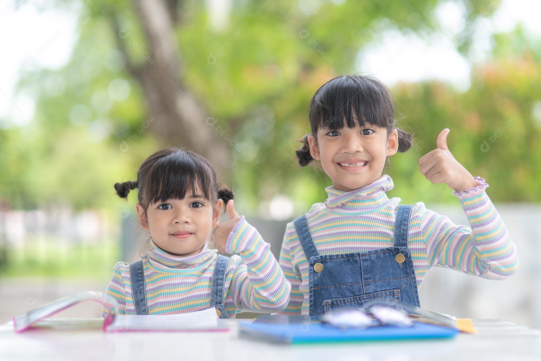 Duas meninas asiáticas estudantes lendo o livro na mesa.