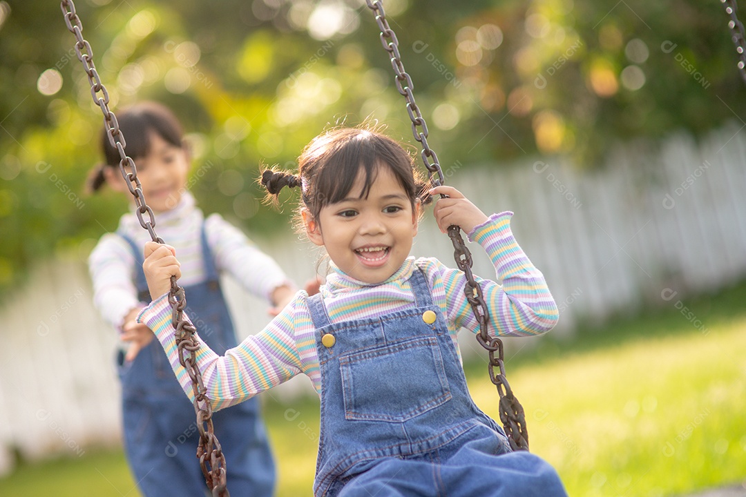 Two cute little sisters having fun on a swing together in a boyfriend.
