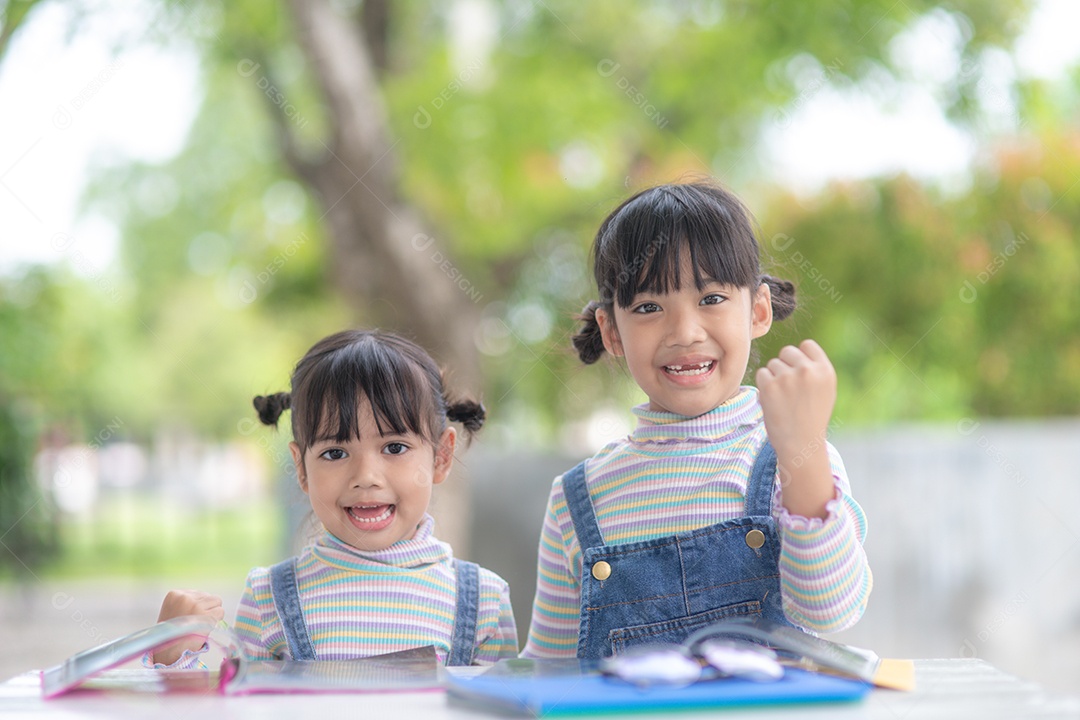 Duas meninas asiáticas estudantes lendo o livro na mesa.