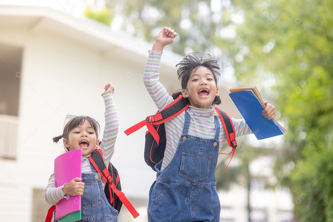 Crianças com mochilas pulando no parque perto da escola.
