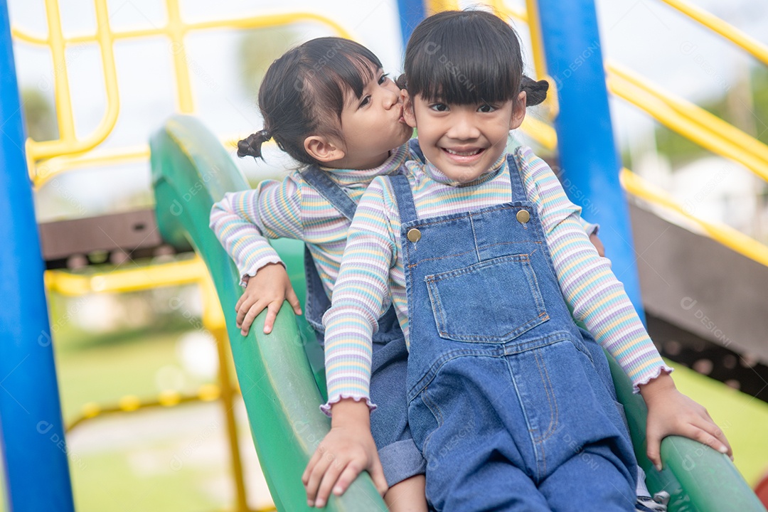 Irmãos bonitos de meninas se divertindo no playground ao ar livre.