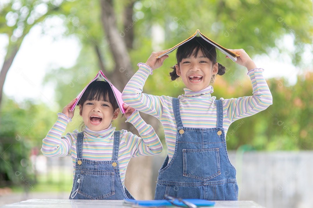 Meninas e irmãs lendo um livro juntas. Adorável asiático