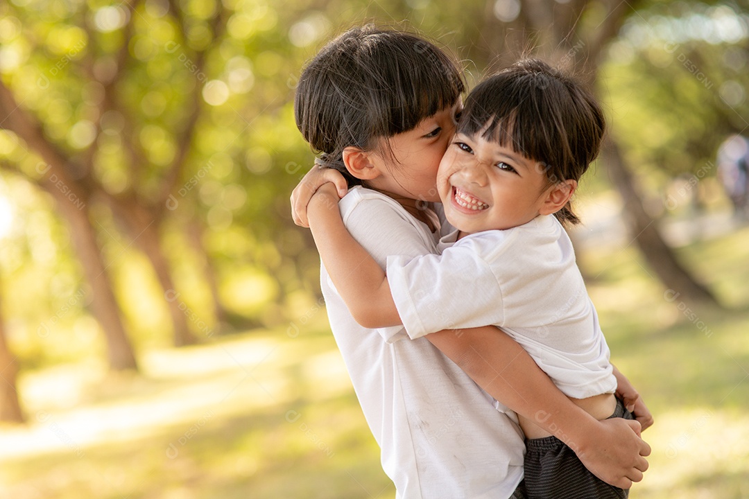 Duas garotinhas asiáticas se abraçando com amor no jardim