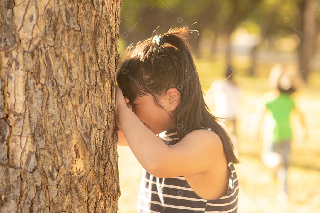 Menina está brincando de esconde-esconde no parque