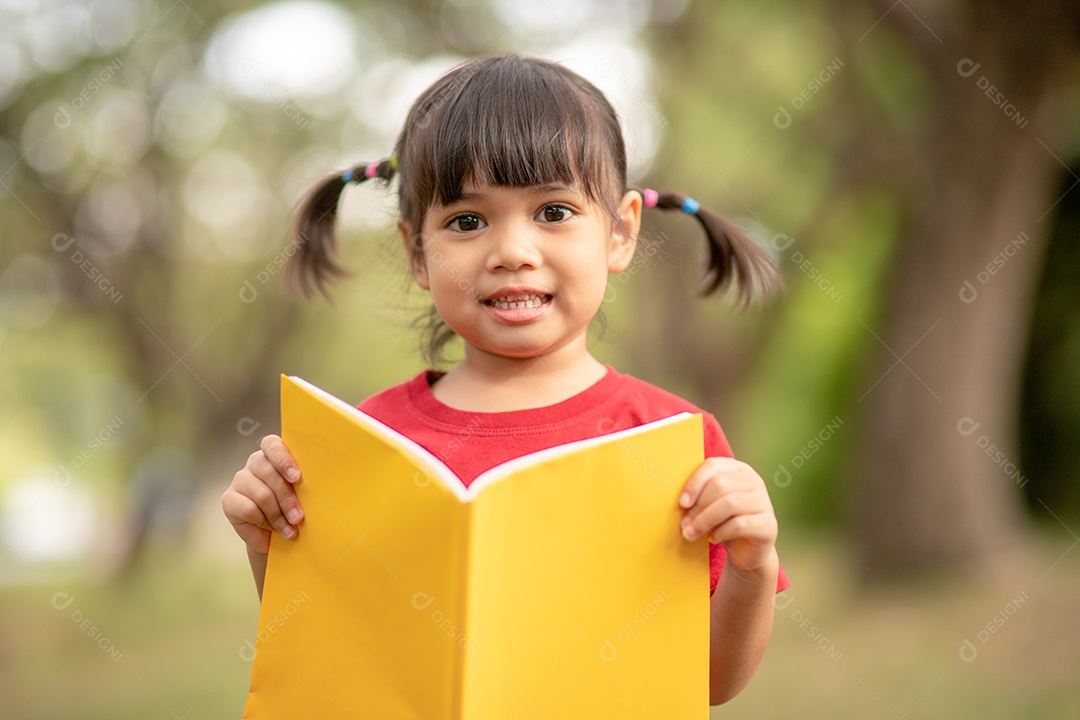 Menina bonitinha lendo livro sobre parque
