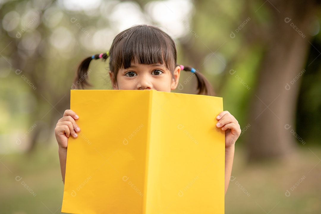 Menina bonitinha lendo livro sobre parque