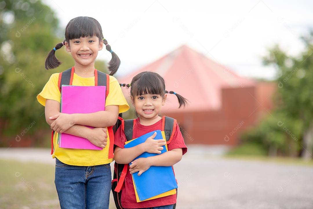 De volta à escola. Duas meninas asiáticas fofas com bolsa escolar segurando livros