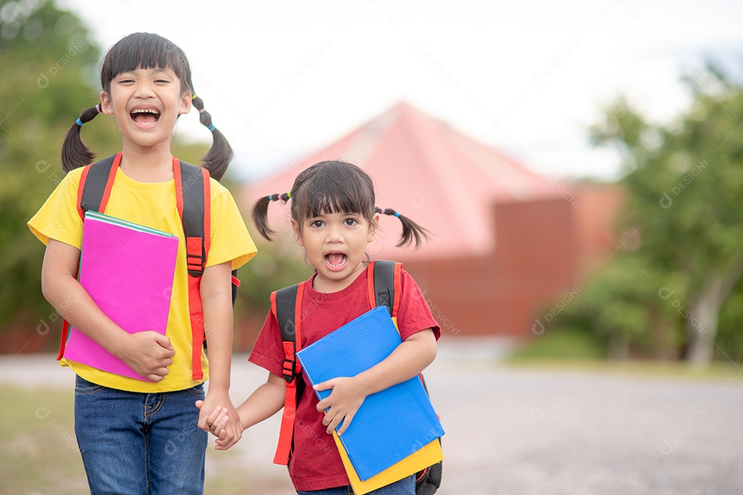 De volta à escola. Duas meninas asiáticas fofas com bolsa escolar segurando livros