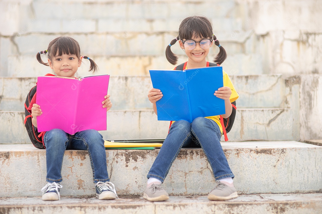 Meninas e irmãs lendo um livro juntos. Adorável asiático