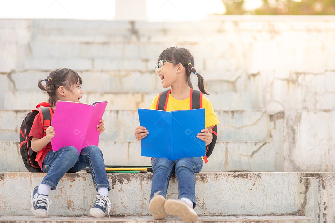 Meninas e irmãs lendo um livro juntos. Adorável asiático