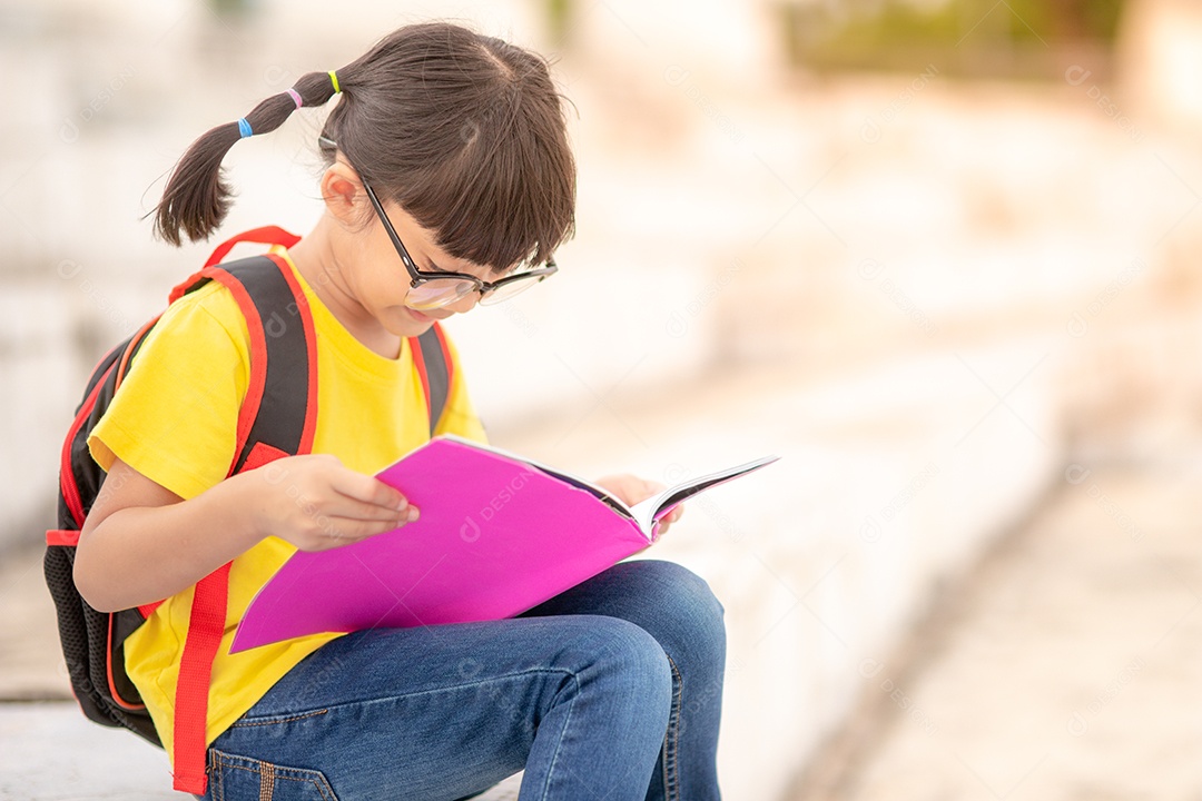 Linda menina jovem inteligente lendo livro criança estudante