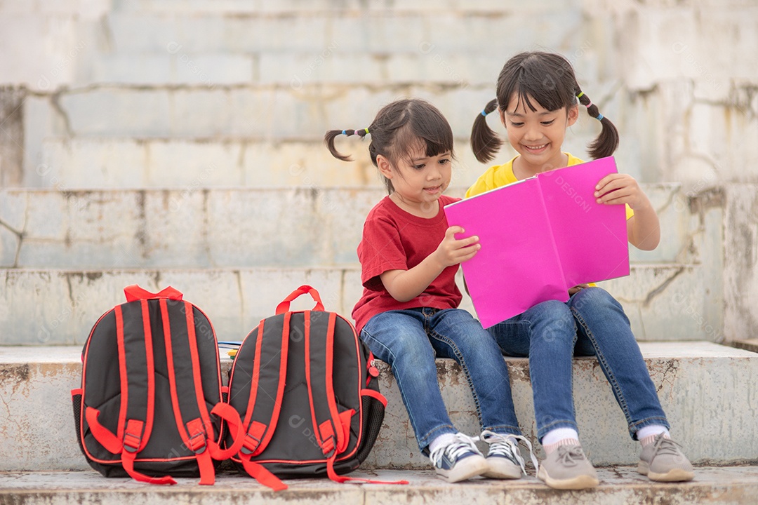 Meninas e irmãs lendo um livro juntas. Adorável asiático