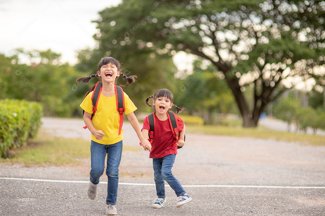 Crianças asiáticas bonitas de mãos dadas enquanto vão para a escola
