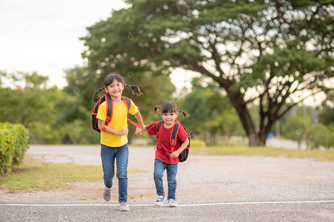 Crianças asiáticas bonitas de mãos dadas enquanto vão para a escola