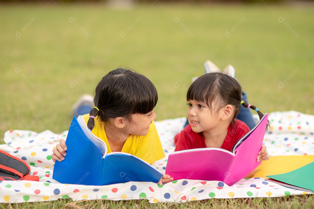 Menina e irmã lendo um livro juntos no parque