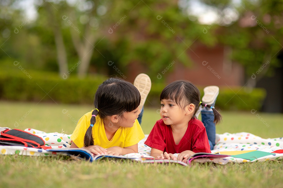 Menina e irmã lendo um livro juntos no parque