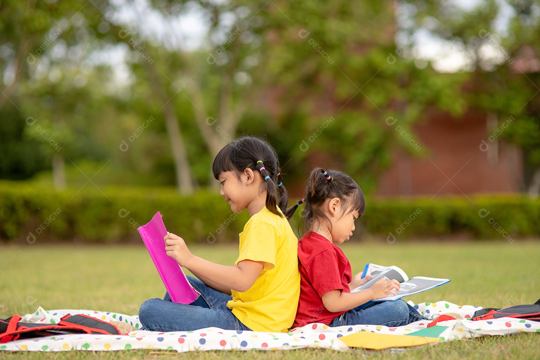 Meninas e irmãs lendo um livro juntos no parque