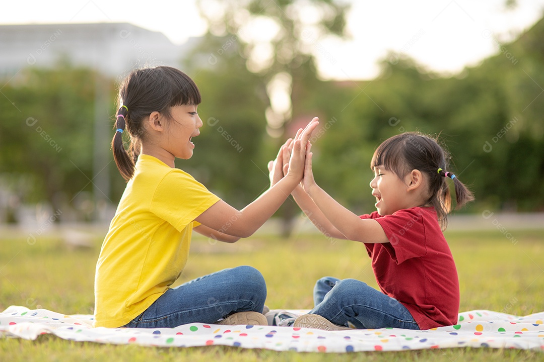 Duas meninas sentadas na grama do parque e jogando