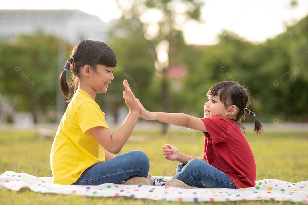 Duas meninas sentadas na grama do parque e jogando