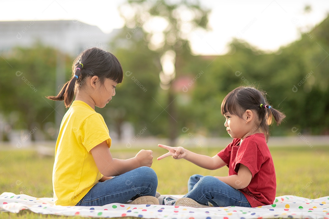 Duas meninas sentadas na grama do parque e jogando