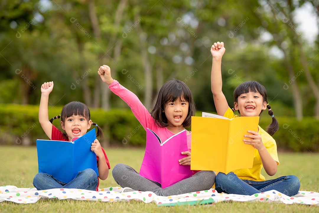 Três crianças lendo no parque.