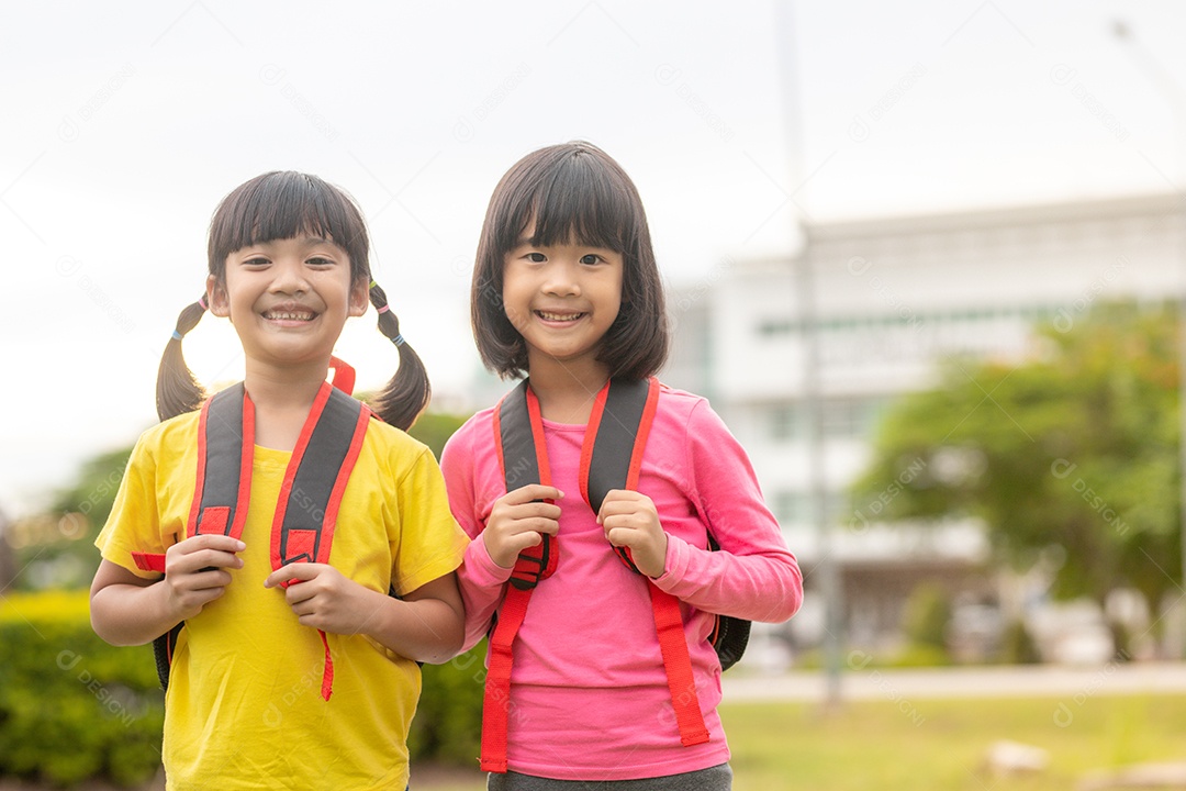 De volta à escola. Duas meninas asiáticas bonitas com mochila escolar.