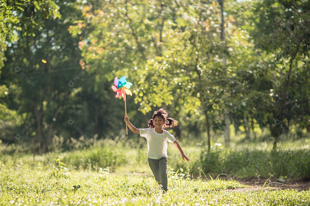 Feliz menina de criança asiática com turbina eólica no jardim