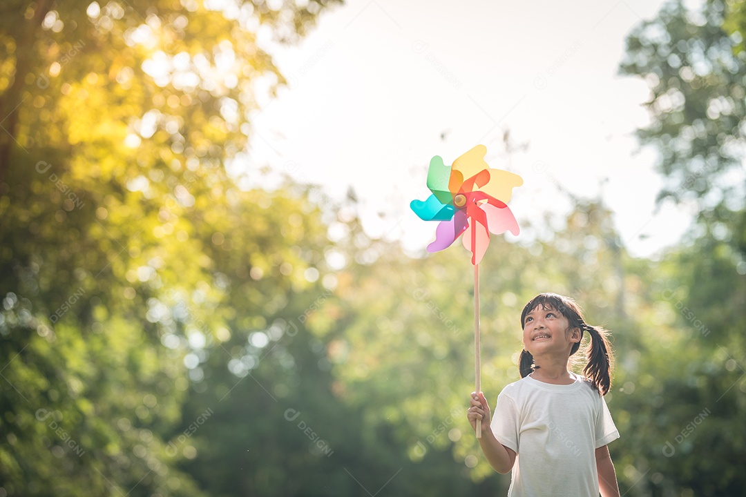 Feliz menina de criança asiática com turbina eólica no jardim