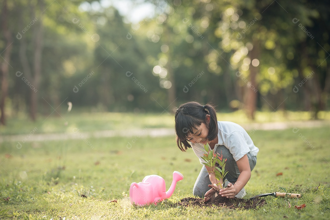 Menina asiática fechada plantando uma árvore na natureza verde