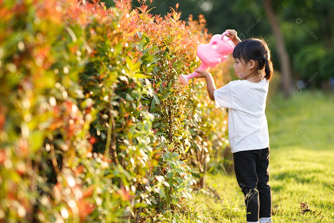 Asian girl pouring water on trees. boy helps take care of plants
