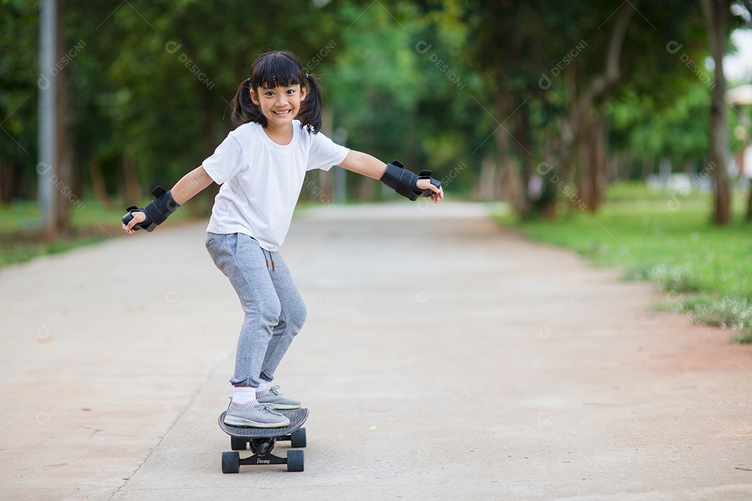 Menina bonitinha jogando skate ou skate de surf no parque de skate