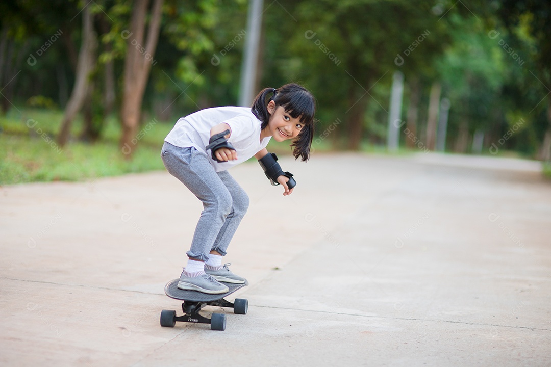 Menina bonitinha jogando skate ou skate de surf no parque de skate