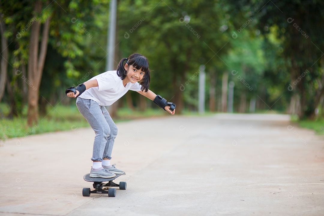 Menina bonitinha jogando skate ou skate de surf no parque de skate