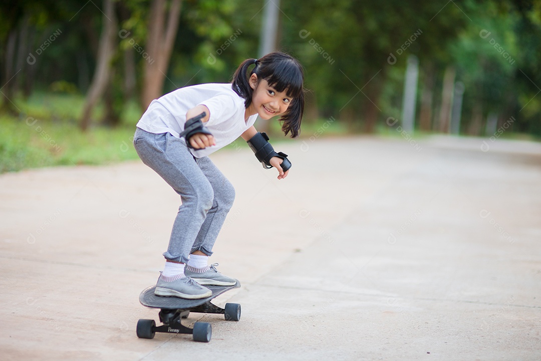 Menina bonitinha jogando skate ou skate de surf no parque de skate