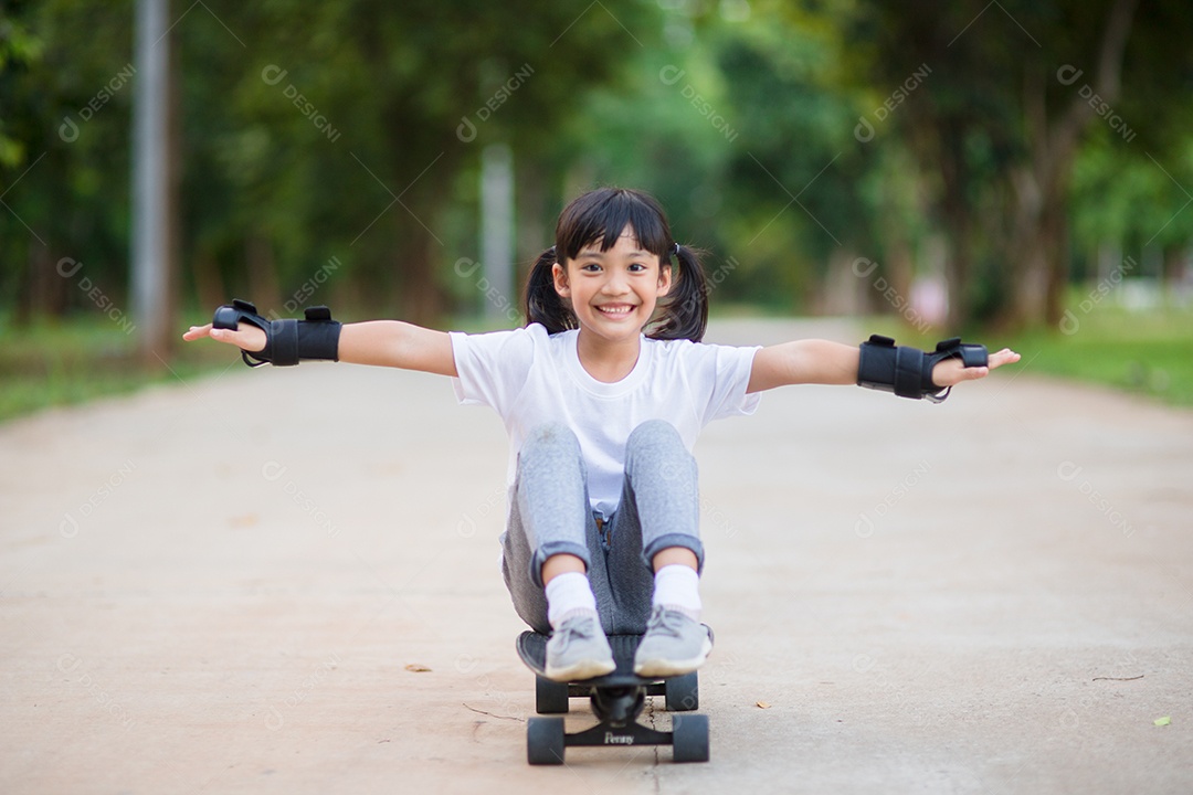 Menina bonitinha jogando skate ou skate de surf no parque de skate