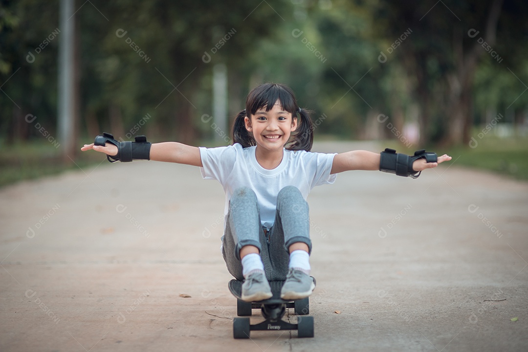 Menina bonitinha jogando skate ou skate de surf no parque de skate