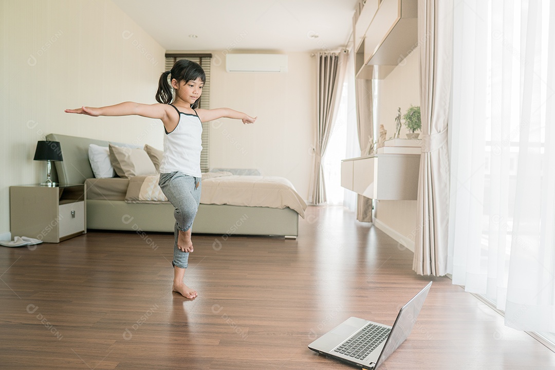 Menina bonitinha em roupas esportivas assistindo vídeo online no laptop