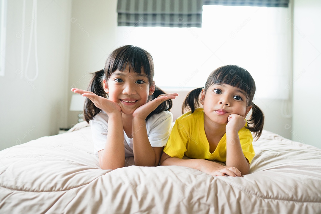 Lindas crianças asiáticas deitadas na cama